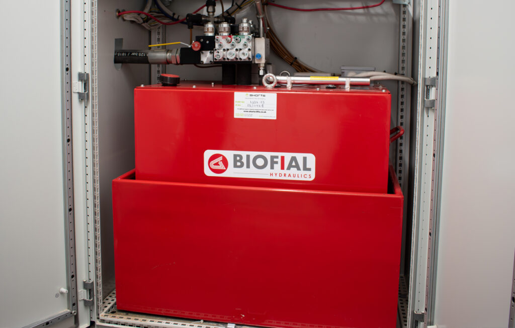 Red storage tank with a label, housed within a metal cabinet, featuring various pipes and connections.