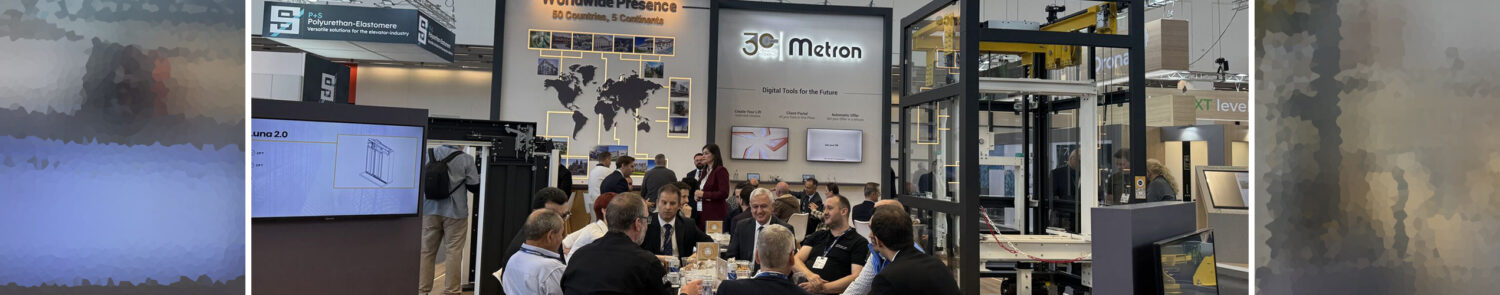 A group of people seated around a table in a conference setting, with displays in the background.