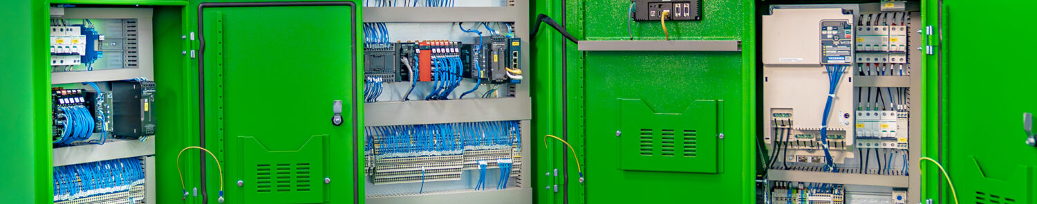 Three green electrical cabinets with visible wiring and control panels inside.