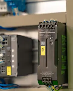 Power supply unit mounted on a control panel with visible wiring and connectors.